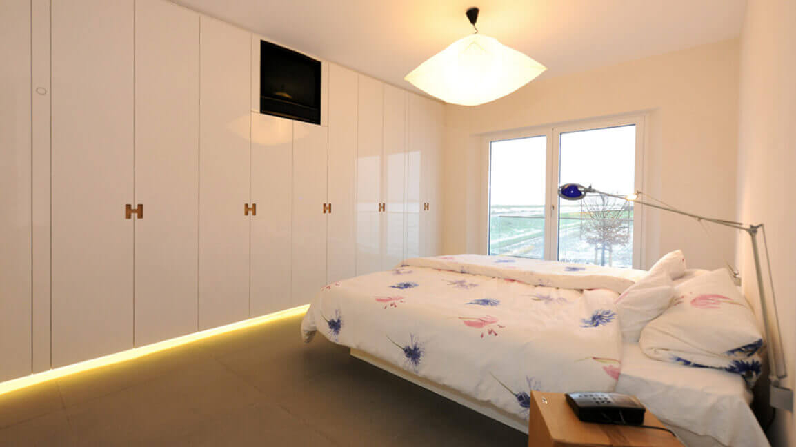 Einbaukleiderschrank mit Hochglanzfronten und individuellen Griffen.